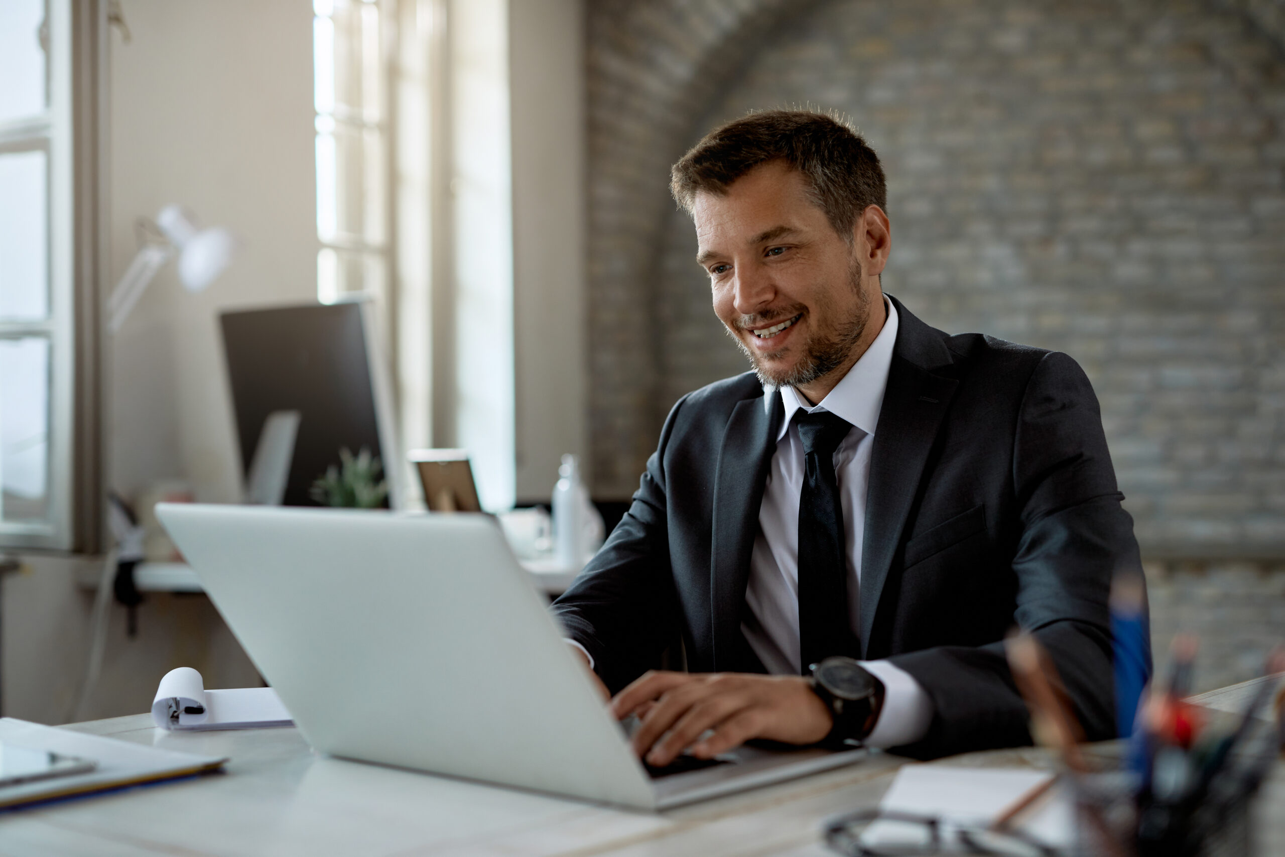 empresario masculino feliz trabajando en una computadora en la oficina